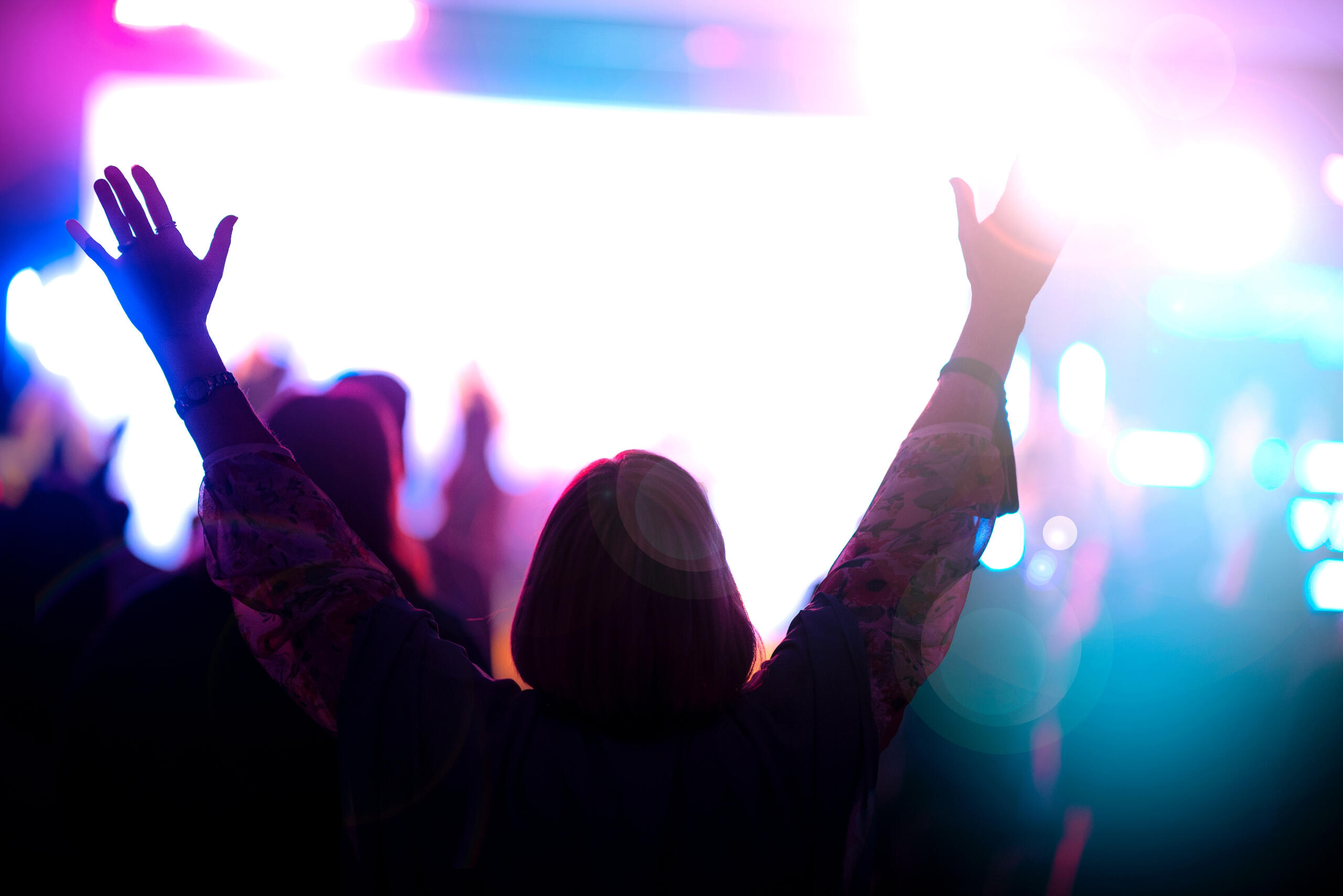 Silhouette of a person in awe of an experience with their hands outstretched overhead.